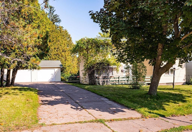 view of property hidden behind natural elements with a garage, fence, an outbuilding, and a front lawn