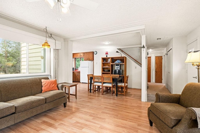 living room with light wood-type flooring, a textured ceiling, and ceiling fan
