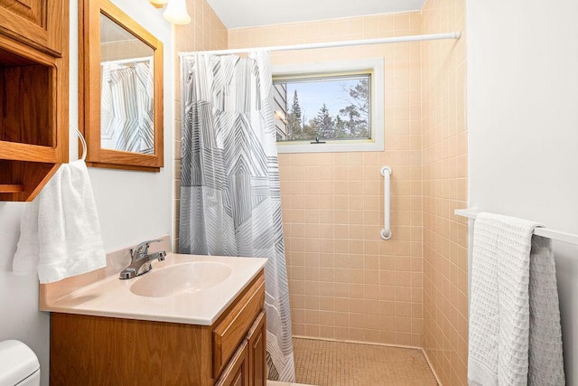 full bath with vanity, a tile shower, and toilet