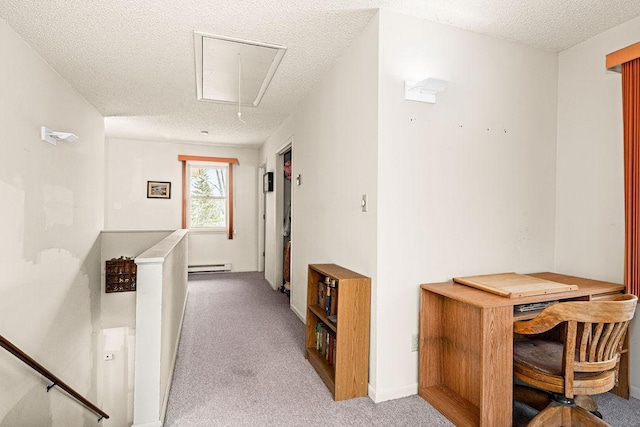 hall featuring attic access, baseboard heating, a textured ceiling, carpet, and an upstairs landing