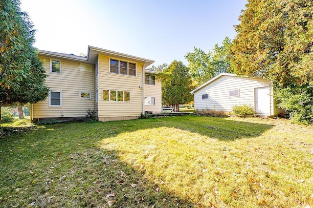 back of house featuring a lawn and an outbuilding