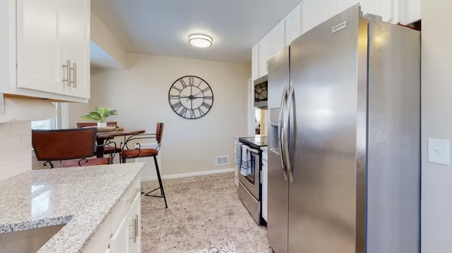 kitchen featuring light stone countertops, white cabinets, and appliances with stainless steel finishes