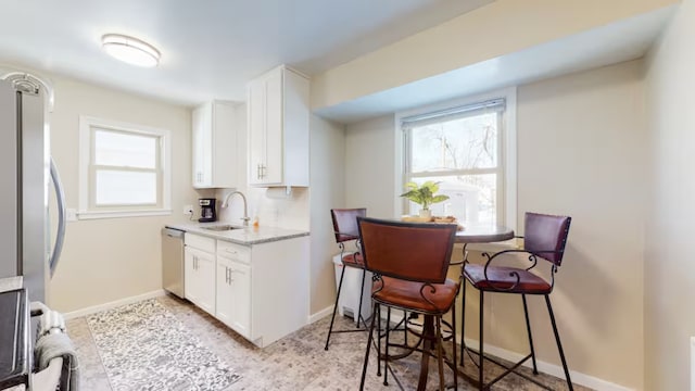 kitchen with stainless steel appliances, sink, white cabinets, and light stone counters