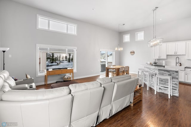 living room featuring dark hardwood / wood-style flooring, sink, a chandelier, and a high ceiling