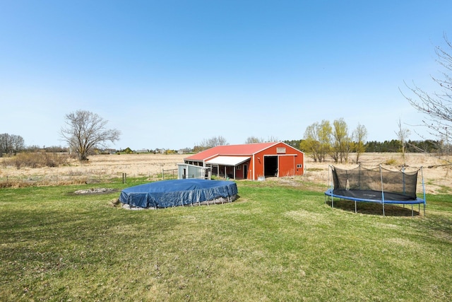 view of yard featuring a pole building, a trampoline, and an outbuilding