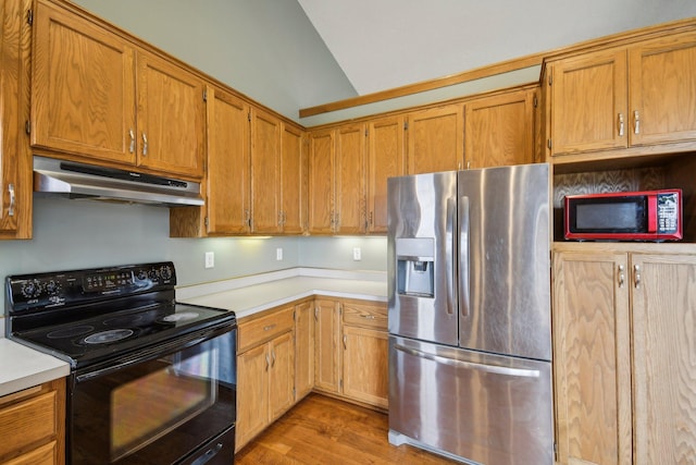 kitchen with stainless steel fridge, light countertops, under cabinet range hood, light wood finished floors, and black / electric stove