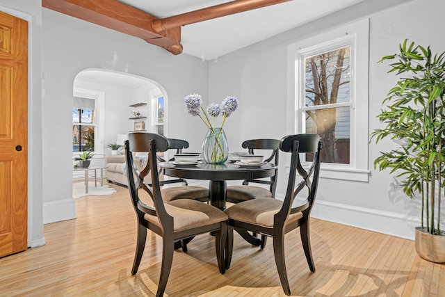 dining space with beamed ceiling and light hardwood / wood-style flooring