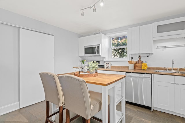 kitchen with butcher block counters, sink, white cabinetry, and appliances with stainless steel finishes