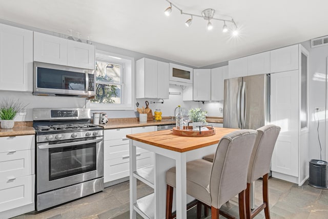 kitchen featuring stainless steel appliances, white cabinetry, and sink