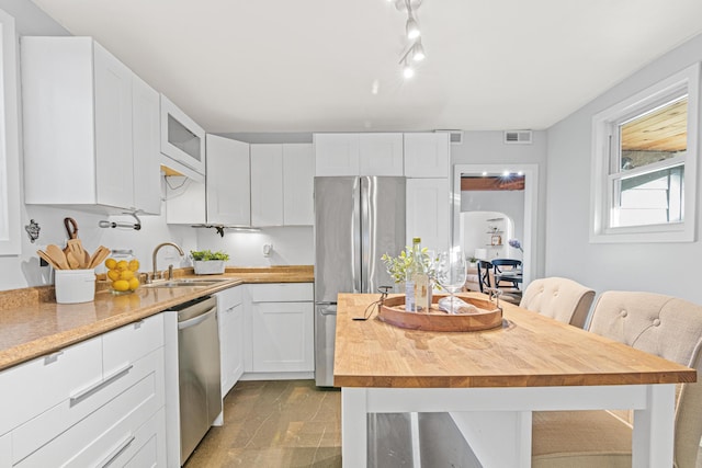 kitchen with a kitchen island, appliances with stainless steel finishes, white cabinetry, sink, and a breakfast bar area