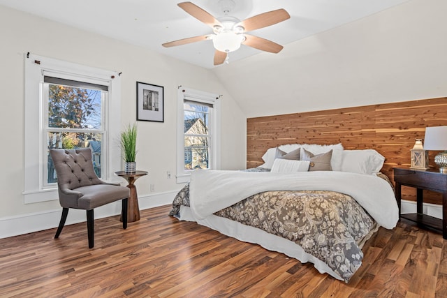 bedroom with dark wood-type flooring, ceiling fan, vaulted ceiling, and wood walls