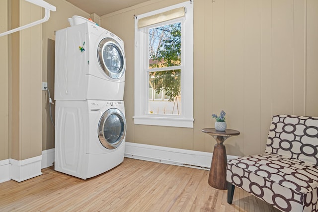 washroom with stacked washer / drying machine and light hardwood / wood-style floors