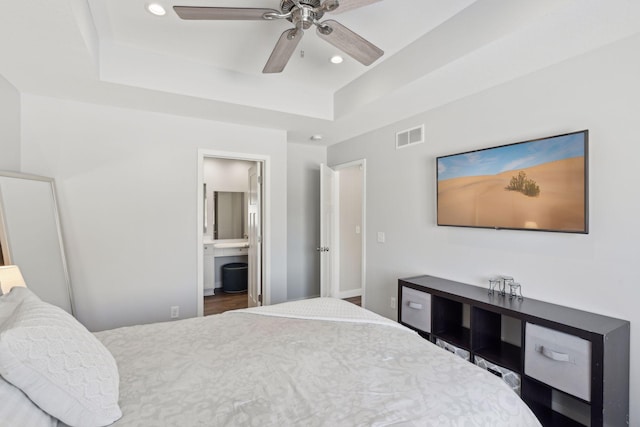 bedroom featuring a tray ceiling, recessed lighting, visible vents, a ceiling fan, and connected bathroom