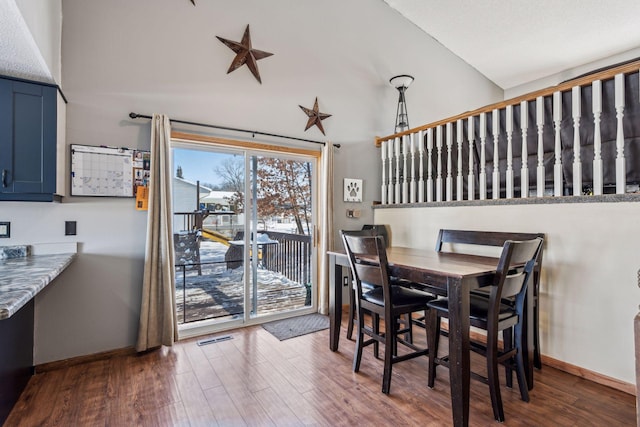 dining area with dark hardwood / wood-style floors and high vaulted ceiling