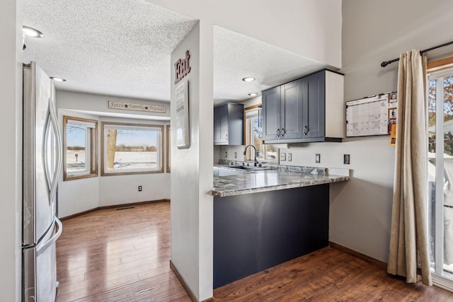 kitchen with sink, gray cabinetry, stainless steel fridge, dark wood-type flooring, and a textured ceiling