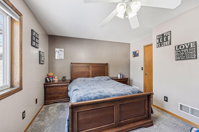 carpeted bedroom featuring multiple windows, a textured ceiling, and ceiling fan