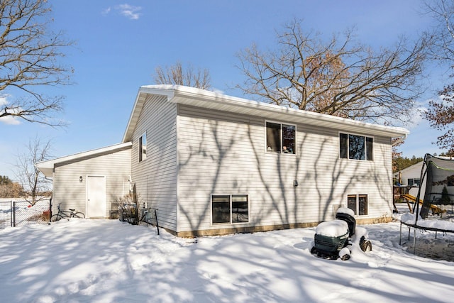 snow covered rear of property featuring a trampoline