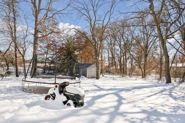 yard covered in snow featuring a storage shed and a trampoline