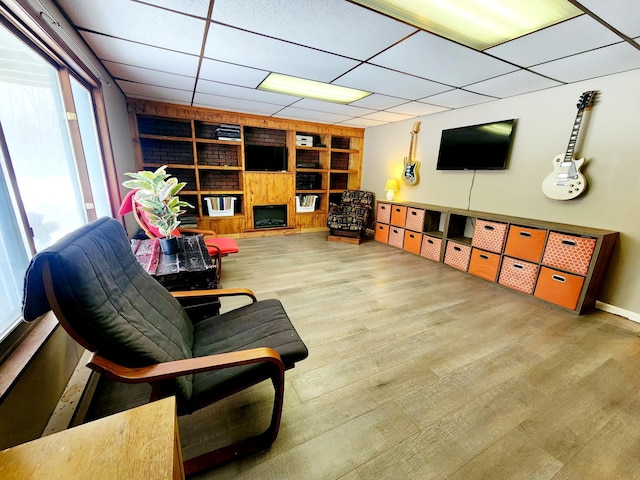 living area with a paneled ceiling, wood-type flooring, and built in features