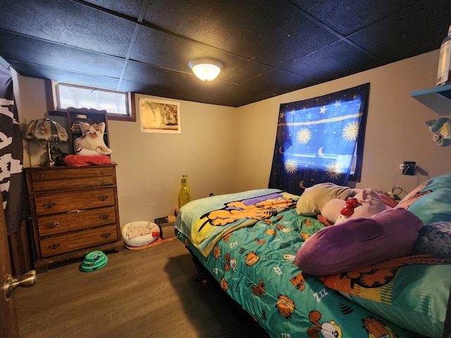 bedroom featuring wood-type flooring and a drop ceiling