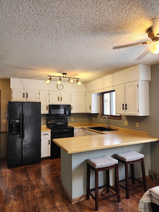 kitchen with a breakfast bar area, sink, kitchen peninsula, and black appliances