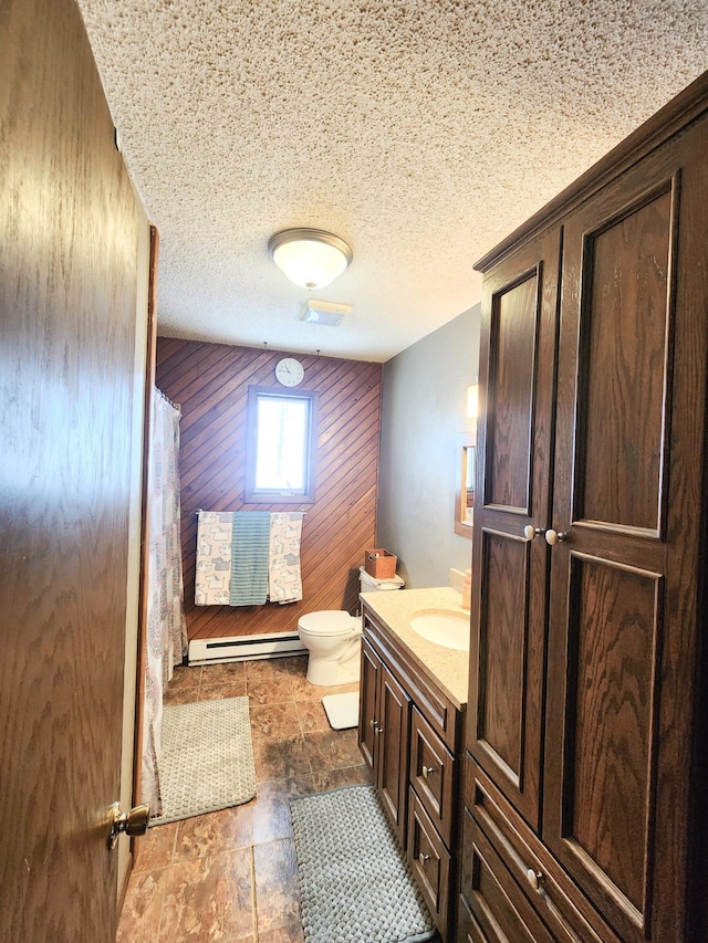 bathroom with a baseboard heating unit, vanity, a textured ceiling, toilet, and wood walls