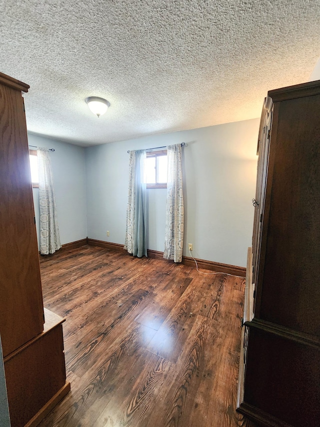 unfurnished room with dark hardwood / wood-style floors and a textured ceiling