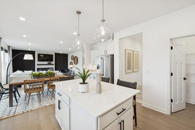 kitchen with pendant lighting, light hardwood / wood-style flooring, a center island, white cabinets, and high end refrigerator