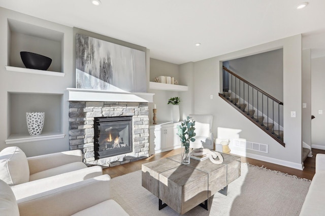 living room with a stone fireplace and dark wood-type flooring