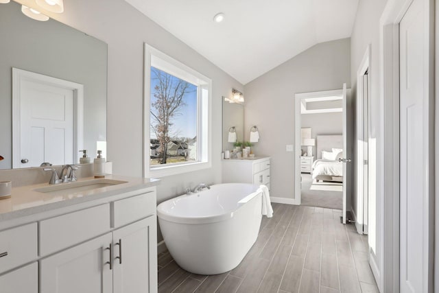 bathroom with vaulted ceiling, a tub, and vanity