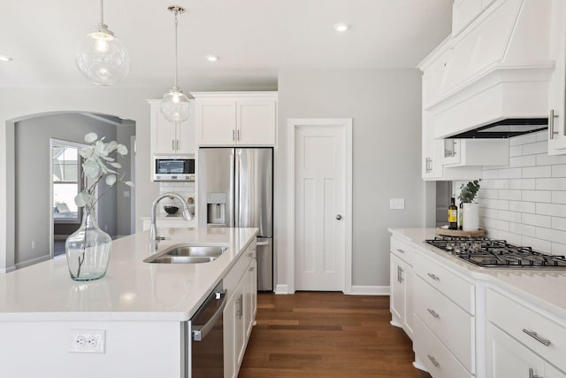 kitchen with an island with sink, white cabinetry, sink, appliances with stainless steel finishes, and pendant lighting