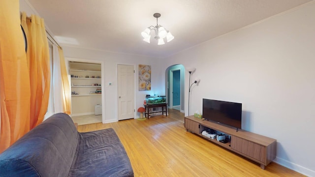 living room with built in shelves, an inviting chandelier, and light hardwood / wood-style flooring