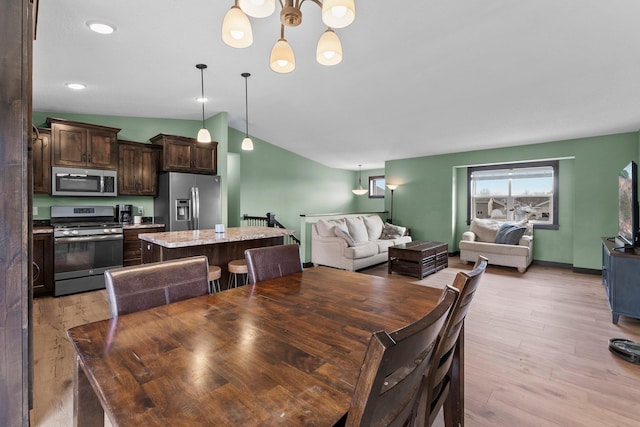 dining space featuring light wood-type flooring, a notable chandelier, recessed lighting, baseboards, and lofted ceiling