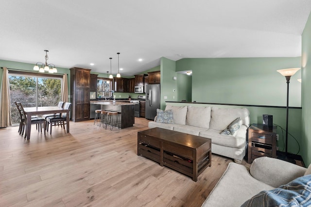 living area featuring vaulted ceiling, recessed lighting, light wood-type flooring, and a chandelier