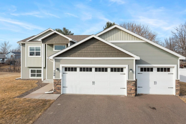 craftsman-style home featuring board and batten siding, a front lawn, aphalt driveway, a garage, and stone siding