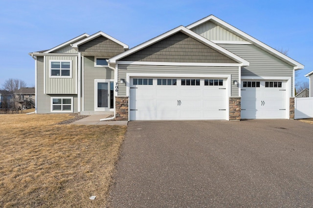 craftsman house featuring aphalt driveway, board and batten siding, a front yard, and a garage