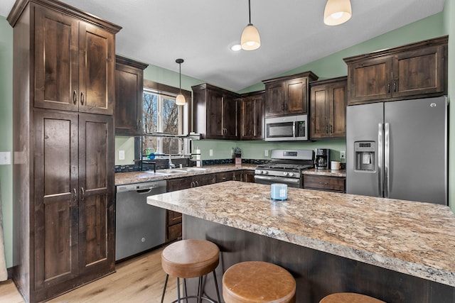 kitchen with a sink, vaulted ceiling, dark brown cabinets, and stainless steel appliances