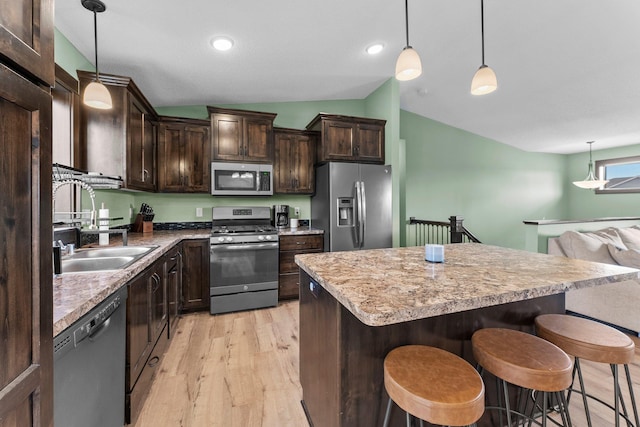 kitchen featuring a kitchen island, dark brown cabinetry, lofted ceiling, a kitchen breakfast bar, and stainless steel appliances