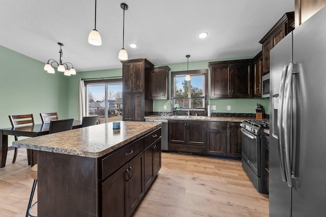 kitchen with a kitchen bar, dark brown cabinets, light wood-style floors, and appliances with stainless steel finishes