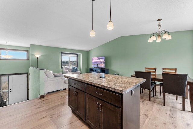 kitchen featuring decorative light fixtures, dark brown cabinets, light wood-type flooring, and vaulted ceiling