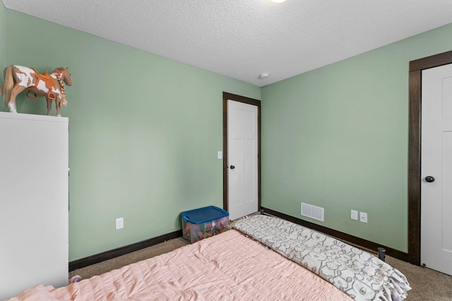 unfurnished bedroom with baseboards, carpet, visible vents, and a textured ceiling