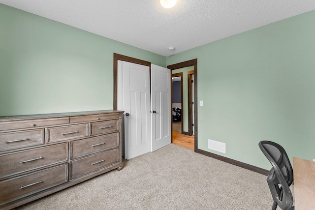 carpeted bedroom featuring visible vents, a textured ceiling, and baseboards