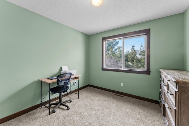 office area with a textured ceiling, baseboards, and light carpet