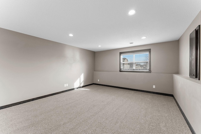 carpeted spare room featuring recessed lighting, baseboards, and a textured ceiling