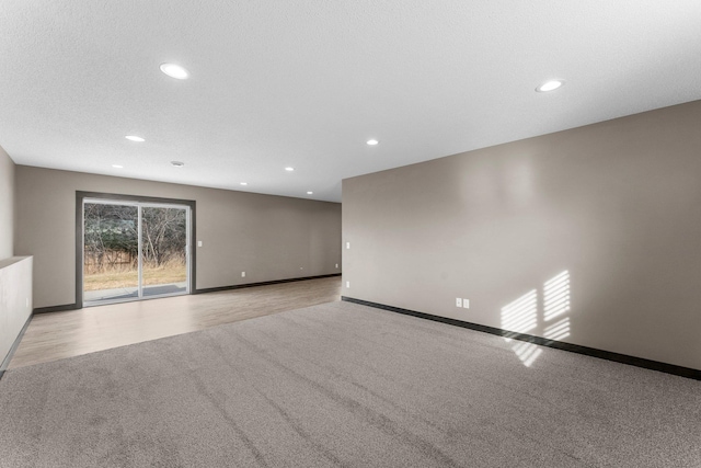 empty room with light wood finished floors, baseboards, light colored carpet, recessed lighting, and a textured ceiling