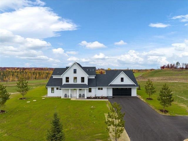 view of front of property featuring a porch, a garage, and a front lawn