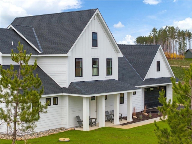 back of property featuring a garage, a patio area, and a lawn