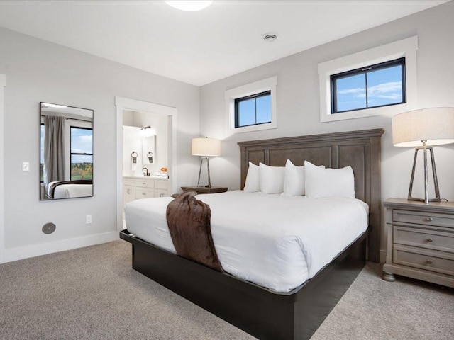 bedroom featuring light carpet, sink, and ensuite bath