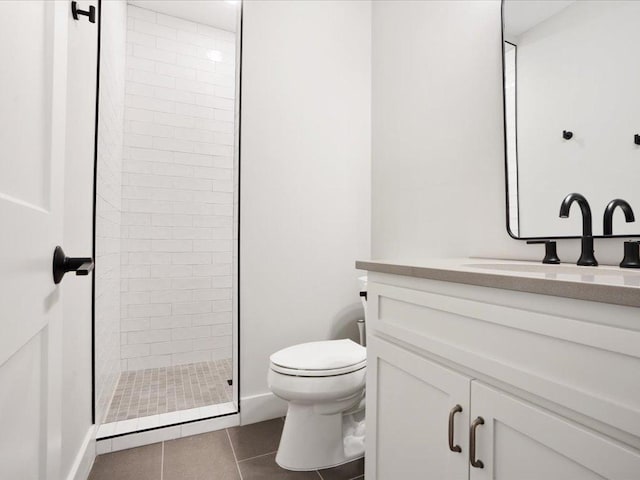 bathroom featuring tile patterned flooring, vanity, toilet, and a tile shower