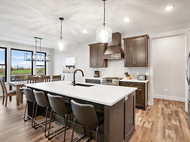 kitchen with pendant lighting, custom range hood, sink, and stainless steel gas range